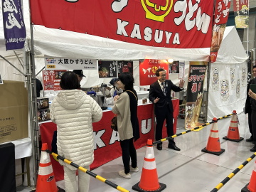 知事がブースの前に立っている